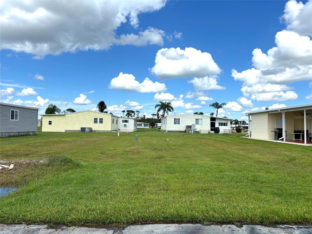 A grassy lot sits between several manufactured homes under a bright blue sky — 626 LA SALA, NORTH PORT, FL