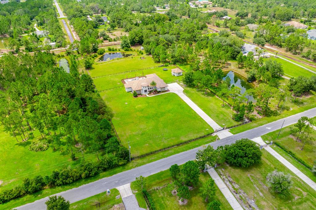 An aerial view shows a single-story house with a pool and pond on a large lot — 4156 BENEDICT AVENUE, ORLANDO, FL