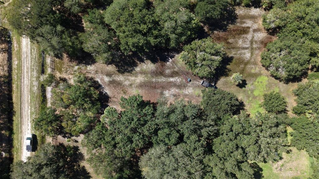 An aerial view shows a dirt driveway, scattered trees, and open land on a rural lot — 20125 NW 300TH STREET, OKEECHOBEE, FL