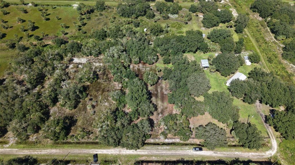 An aerial view shows a wooded lot with several small structures and a dirt road — 20125 NW 300TH STREET, OKEECHOBEE, FL