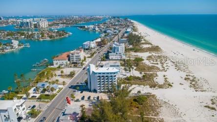 An aerial view of a pink beach house with a gray roof near the ocean — 10200 GULF BOULEVARD, TREASURE ISLAND, FL