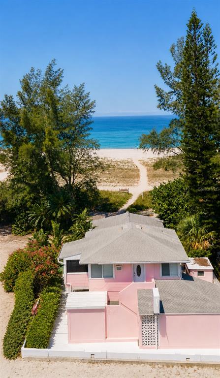 An aerial view shows a coastal road, a multi-story building, and a sandy beach — 10200 GULF BOULEVARD, TREASURE ISLAND, FL