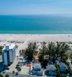 A pink house sits behind a large, sandy yard with lush green landscaping — 10200 GULF BOULEVARD, TREASURE ISLAND, FL