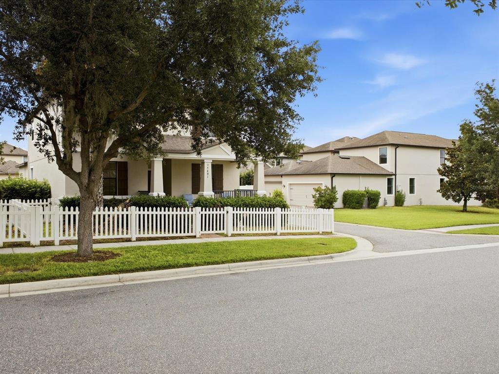 A two-story house with a white picket fence and a large tree in the front yard — 15401 PORTER ROAD, WINTER GARDEN, FL