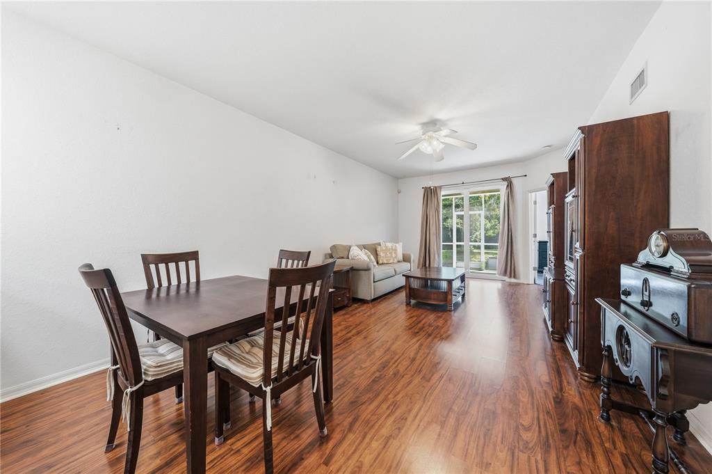 A dining and living area with wood-look flooring, a wooden table, and a sofa — 22128 LITTLE LAGOON COURT, LUTZ, FL