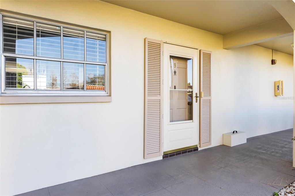 A white exterior wall features a window, a front door with shutters, and a porch — 19029 US HIGHWAY 19 N UNIT 7-9, CLEARWATER, FL
