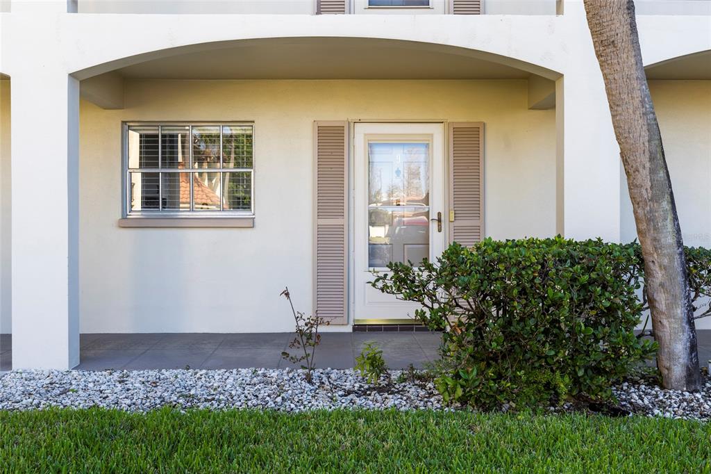 The exterior view shows a ground-level apartment entrance with a window, door, and landscaping — 19029 US HIGHWAY 19 N UNIT 7-9, CLEARWATER, FL