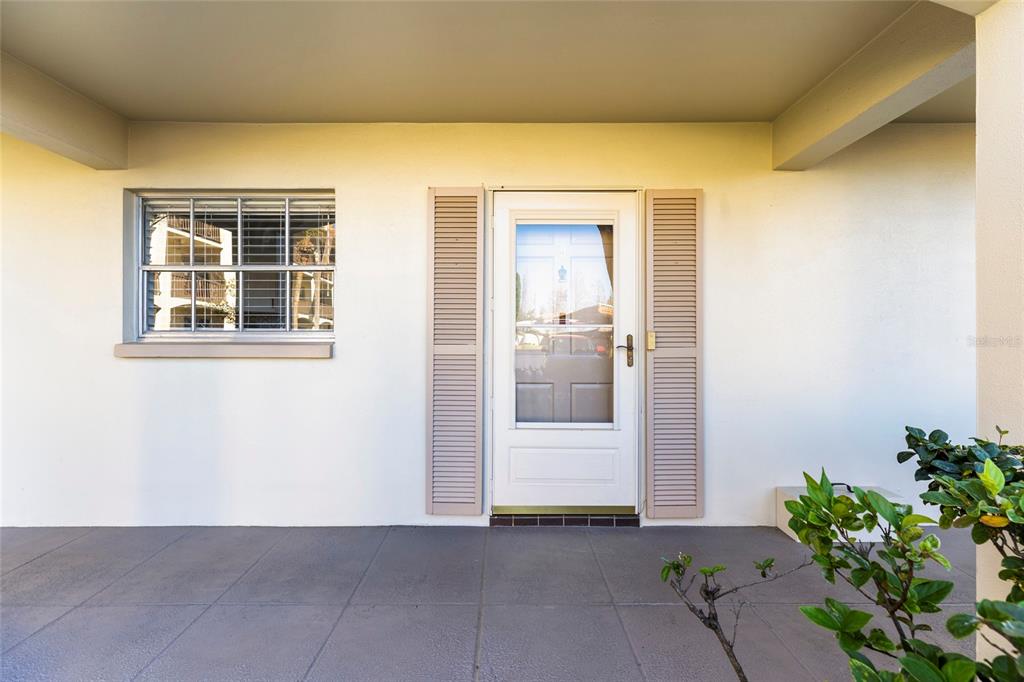 A covered porch features a white front door with shutters and a single window — 19029 US HIGHWAY 19 N UNIT 7-9, CLEARWATER, FL