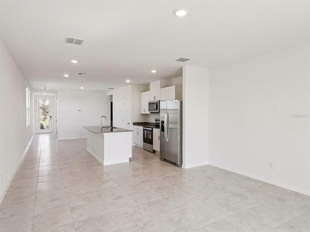 A kitchen with white cabinets, stainless steel appliances, and a granite-topped island on tile flooring — 729 IMPALA ROAD, LAKE ALFRED, FL