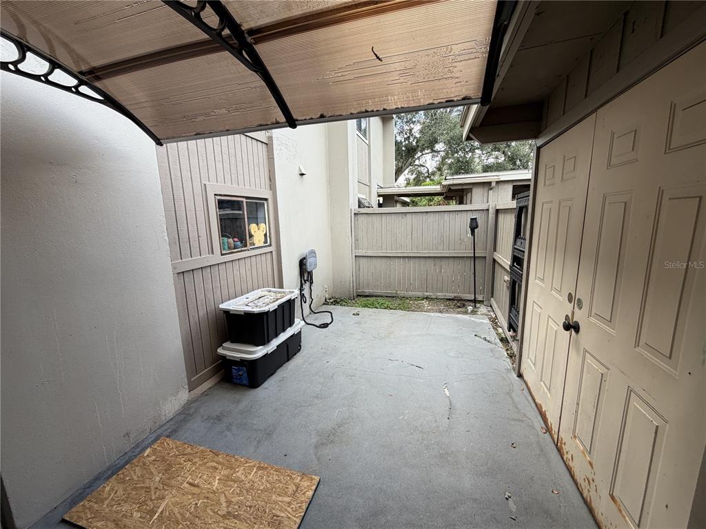 A concrete patio area features a storage shed, a small window, and a partial awning — 7925 PINE DRIVE UNIT 33, TEMPLE TERRACE, FL