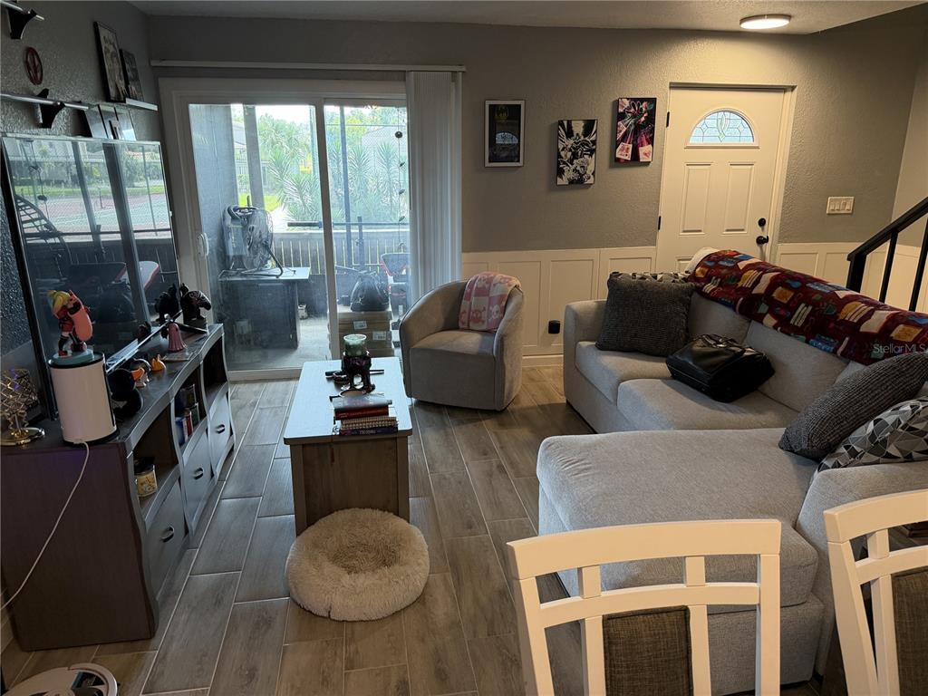 A living room features wood-look tile flooring, a gray sectional sofa, and a sliding glass door — 7925 PINE DRIVE UNIT 33, TEMPLE TERRACE, FL
