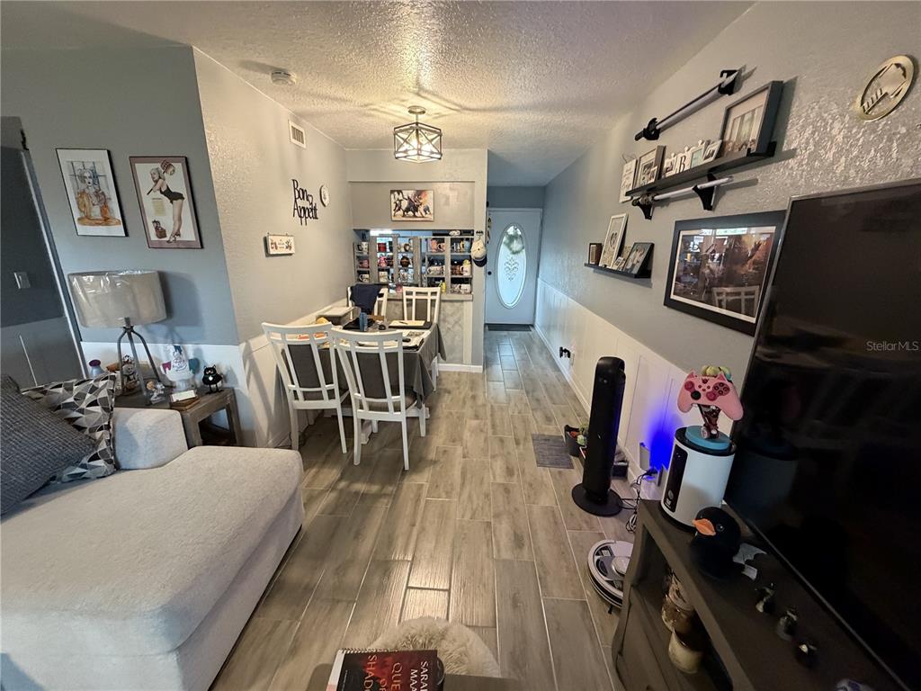A living room and dining area with light wood-look tile flooring and white wainscoting — 7925 PINE DRIVE UNIT 33, TEMPLE TERRACE, FL