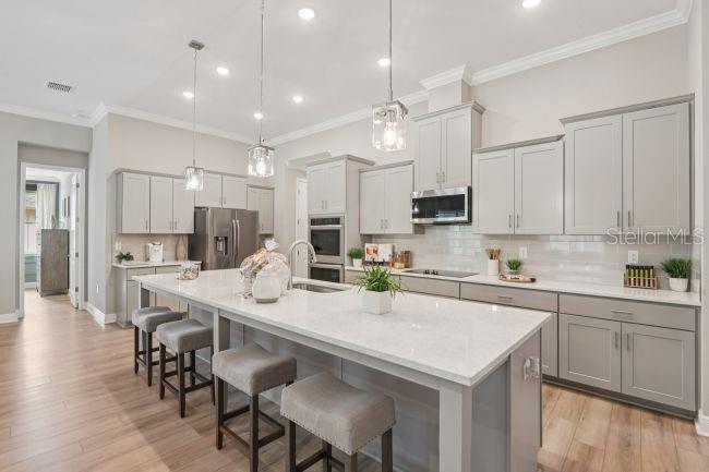 A modern kitchen features light gray cabinets, a large quartz island, and wood-look flooring — 20 FERNON DRIVE, PALM COAST, FL