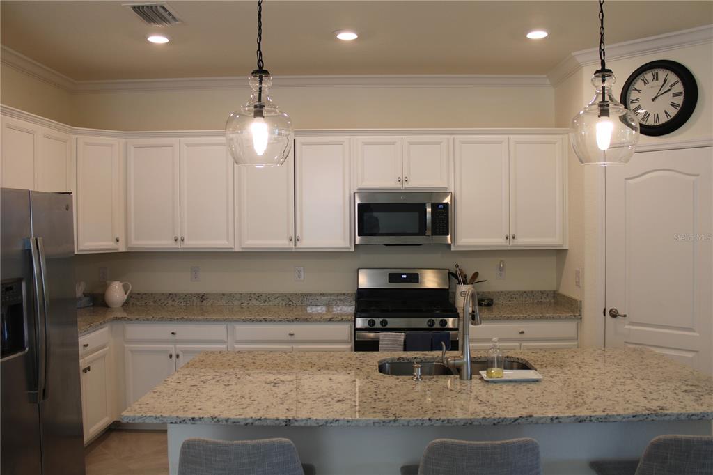 A kitchen features white cabinets, granite countertops, stainless steel appliances, and a central island — 6647 CLAIRBORNE LANE, BRADENTON, FL