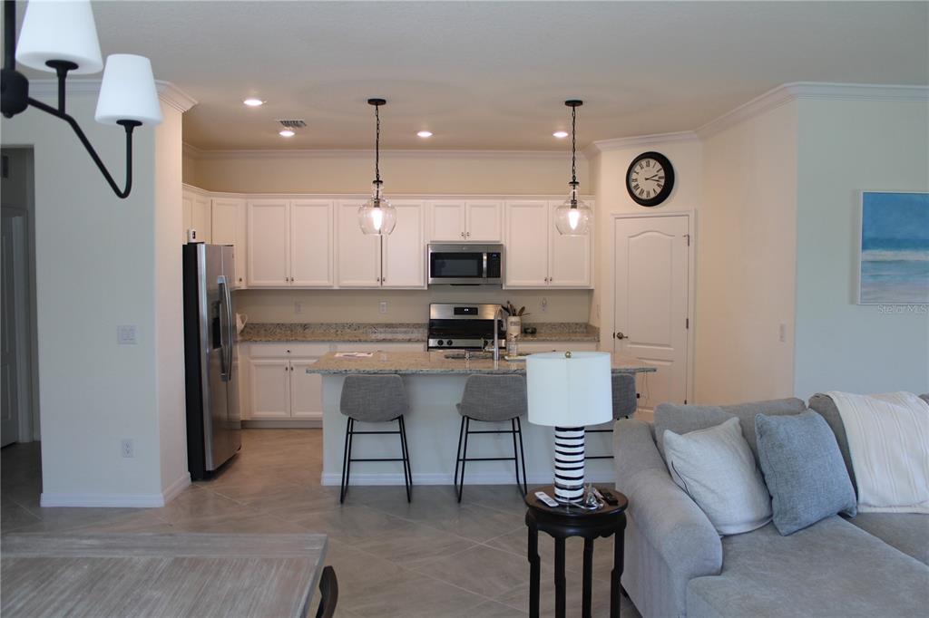 A kitchen features white cabinets, granite countertops, stainless steel appliances, and a breakfast bar island — 6647 CLAIRBORNE LANE, BRADENTON, FL