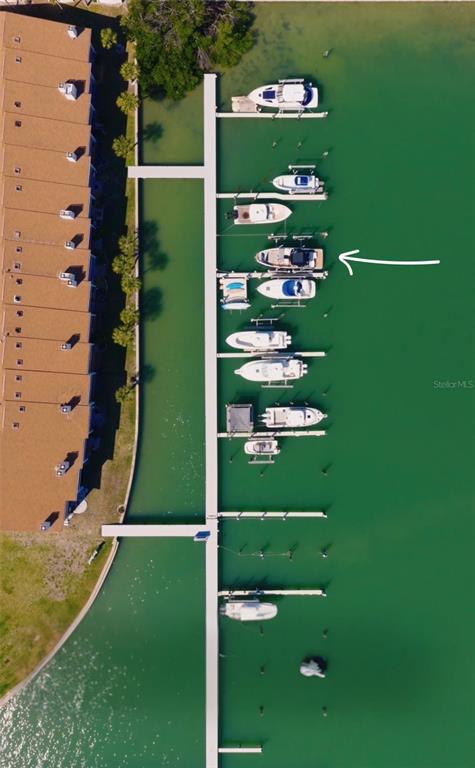 An aerial view shows a waterfront condominium complex with a boat dock and tennis courts — 117 YACHT CLUB LANE, TIERRA VERDE, FL