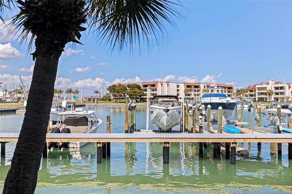 A wooden boat dock with several boats moored in the water under a blue sky — 117 YACHT CLUB LANE, TIERRA VERDE, FL