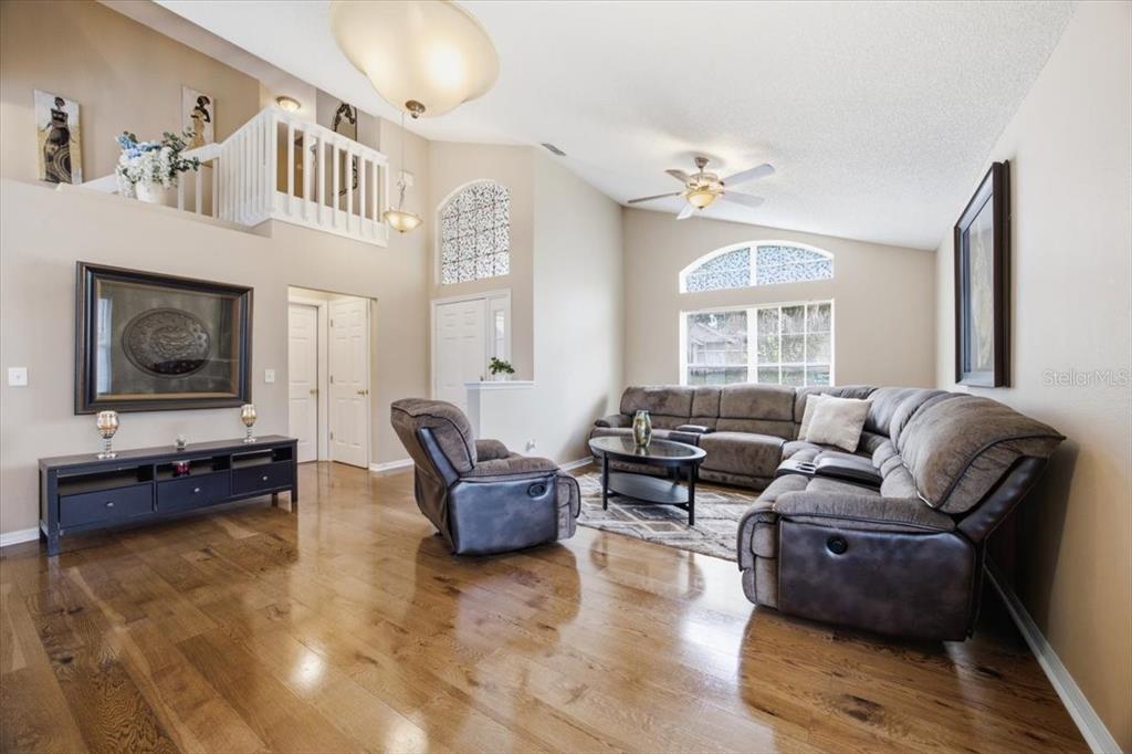 A view from an open doorway into a living area with hardwood floors and vaulted ceilings — 227 DILLON WAY, DAVENPORT, FL