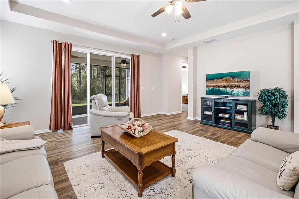 A living room features light-colored sofas, a wooden coffee table, and sliding glass doors — 762 RUSTIC MILL DRIVE, ST AUGUSTINE, FL