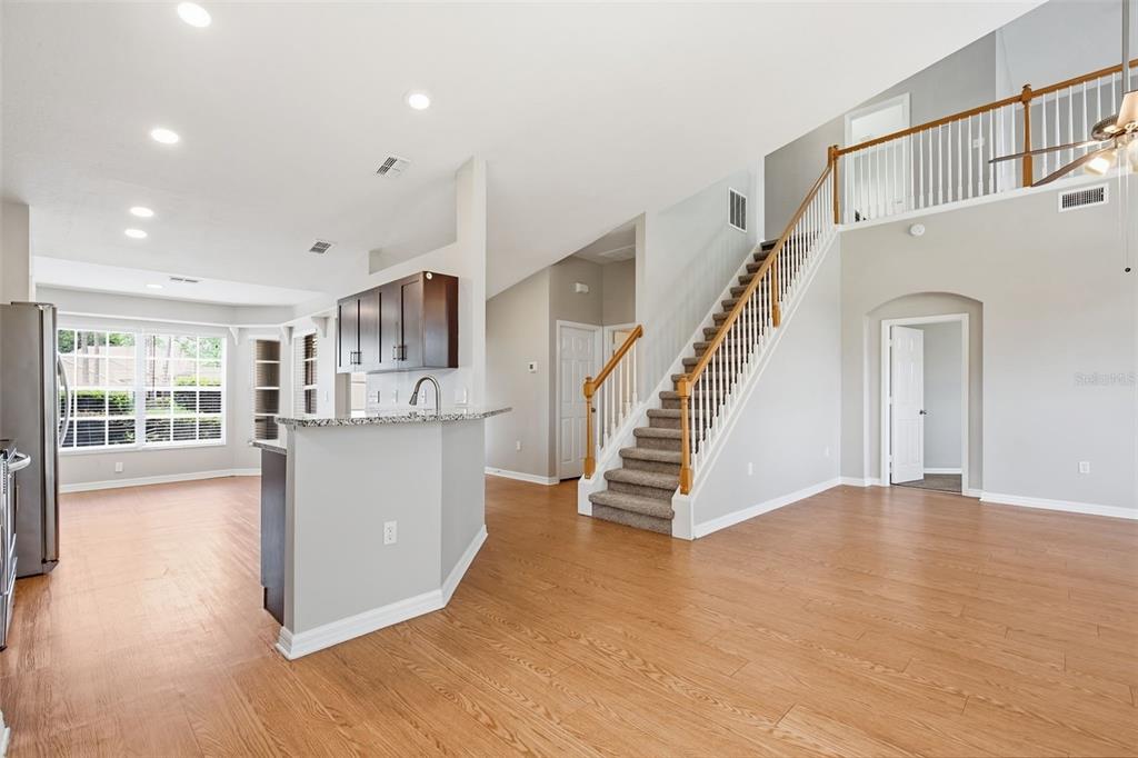 A kitchen with dark cabinets and a breakfast bar overlooks a living area with stairs — 7444 MOORGATE COURT, NEW PORT RICHEY, FL