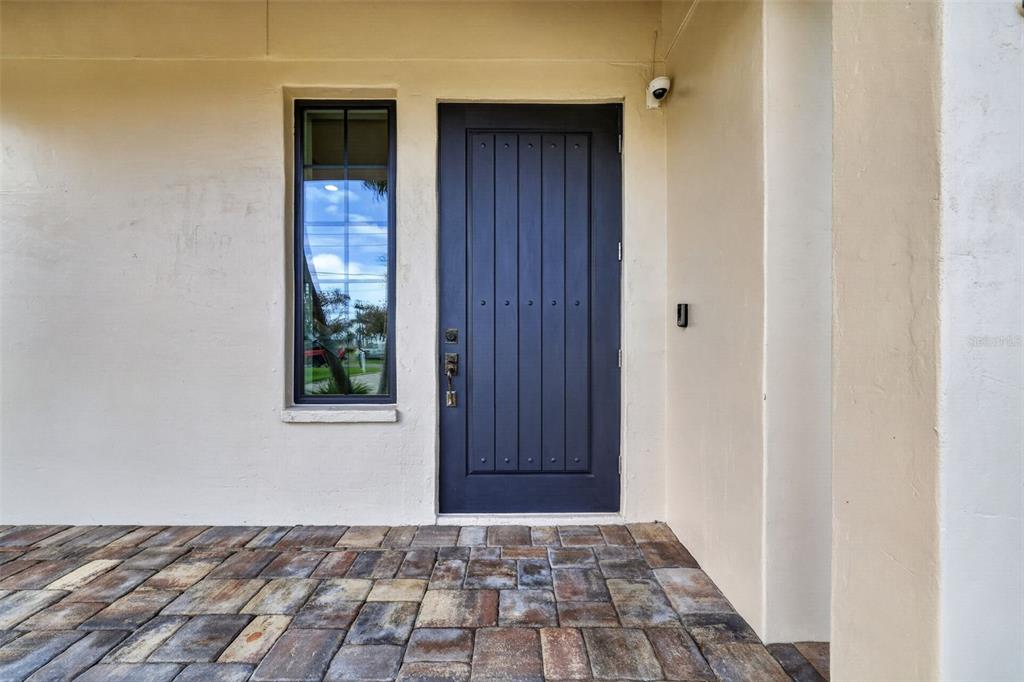 A dark blue front door with a side window sits on a paved porch — 13 TREASURE LN, TREASURE ISLAND, FL