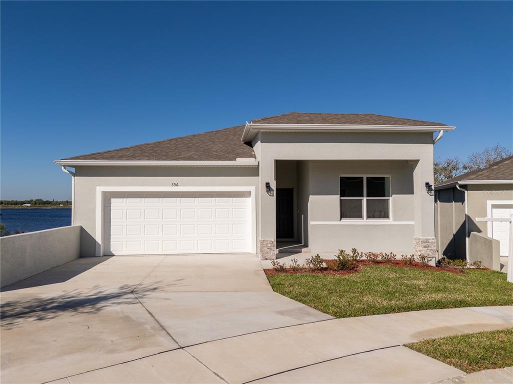 A single-story house with a white garage, gray stucco exterior, and a small front lawn — 356 CHEROKEE AVENUE, HAINES CITY, FL