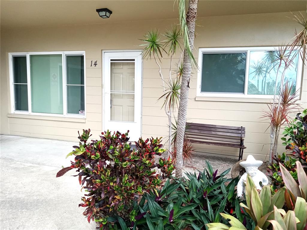 The exterior of a ground-level unit features a white door labeled 14, windows, and landscaping — 2464 AUSTRALIA WAY E UNIT 14, CLEARWATER, FL