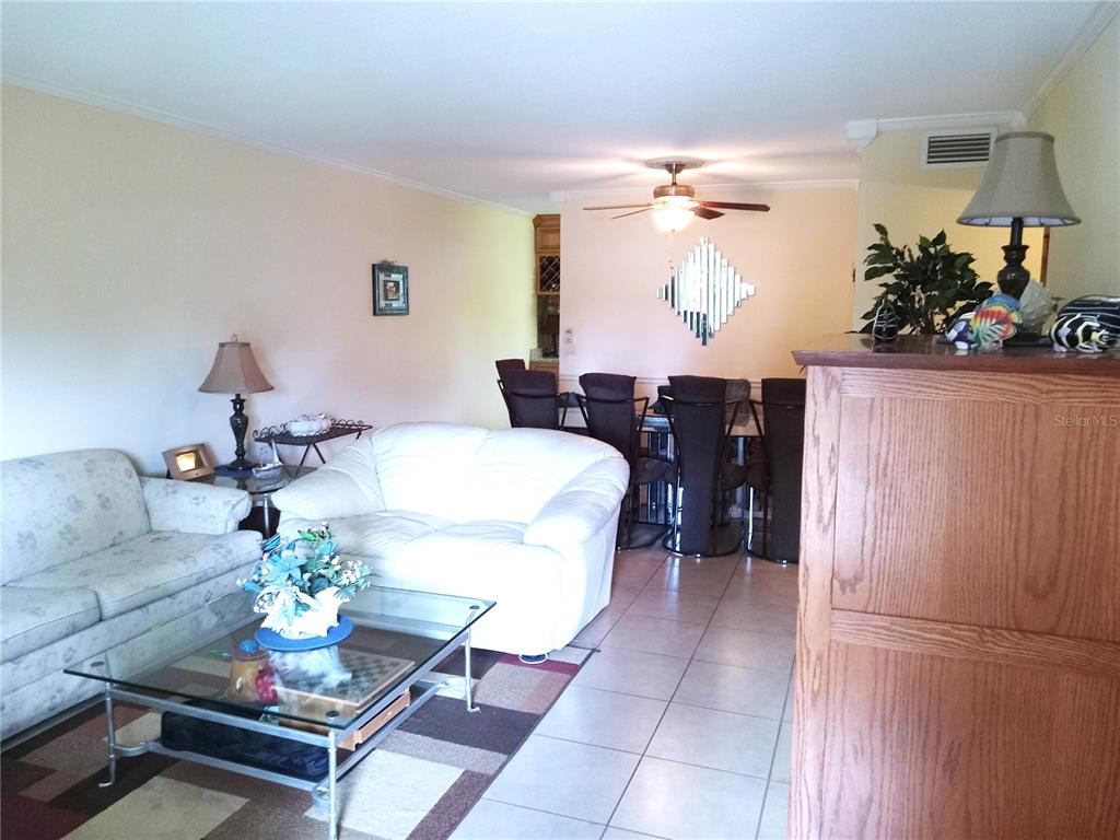 A living room with a white sofa, glass coffee table, and adjacent dining area — 2464 AUSTRALIA WAY E UNIT 14, CLEARWATER, FL