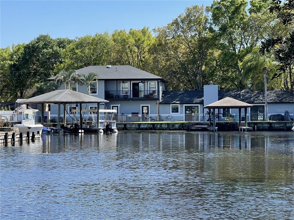 A two-story gray house with a large lawn, mature trees, and an attached garage — 176 MAPLE AVENUE, PALM HARBOR, FL