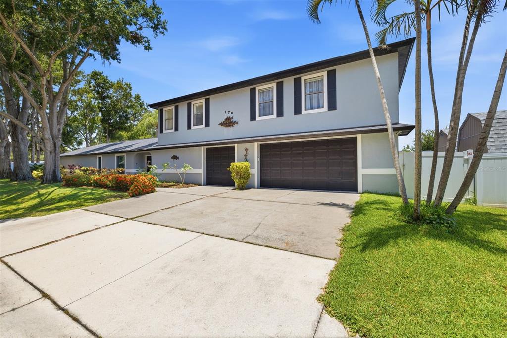 A gray house exterior features a stone walkway, a rocking chair, and a double door — 176 MAPLE AVENUE, PALM HARBOR, FL
