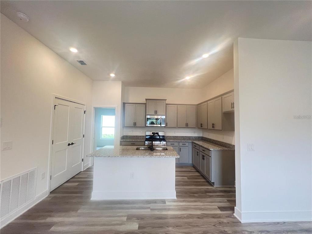 A kitchen features gray cabinets, granite countertops, a central island, and wood-look flooring — 3648 LINDBERGH STREET, LAKELAND, FL