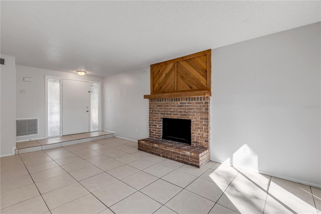 A living room features a brick fireplace with a wood accent wall and tile flooring — 1124 MILL RUN CIRCLE, APOPKA, FL