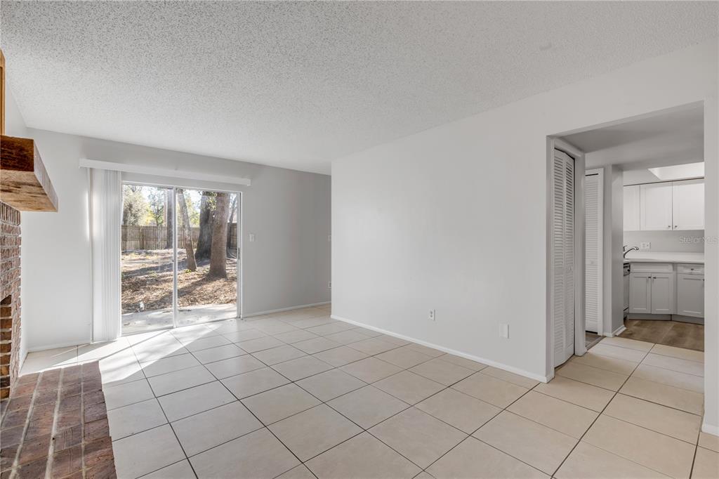 A living room with tile floors, a brick fireplace, and a sliding glass door to outside — 1124 MILL RUN CIRCLE, APOPKA, FL