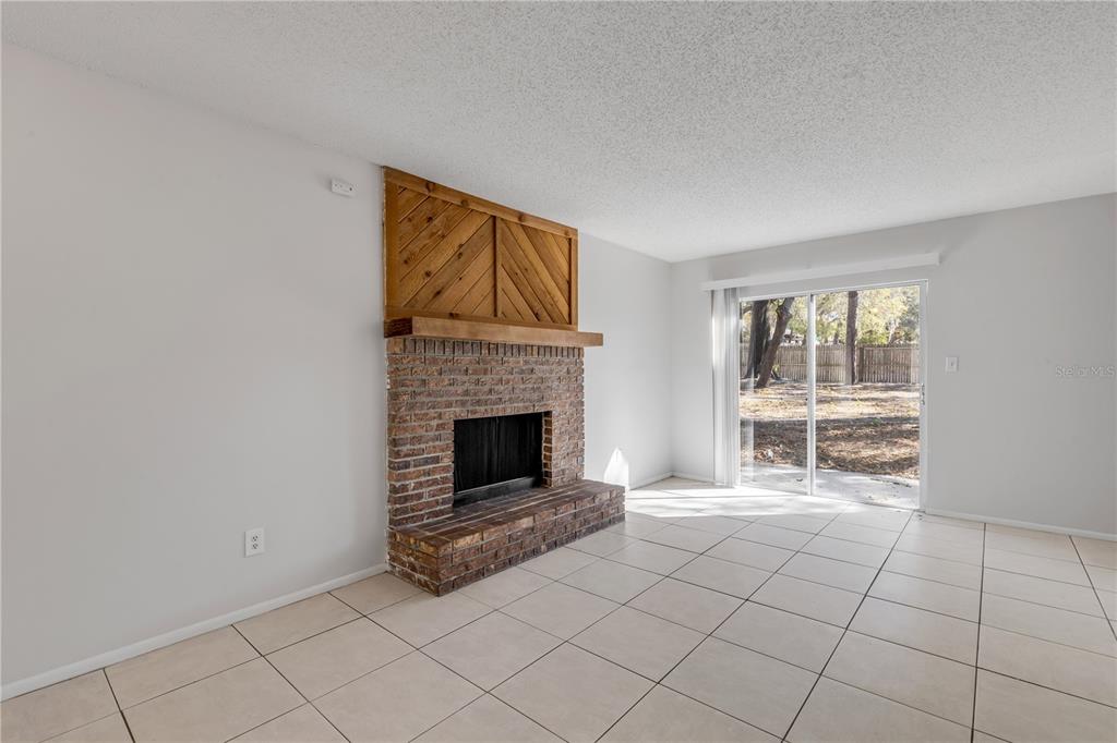 A living room features a brick fireplace with a wooden accent wall and tile flooring — 1124 MILL RUN CIRCLE, APOPKA, FL