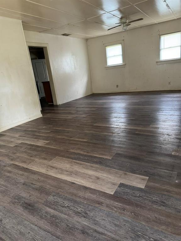 A living and dining room with wood-look flooring, two ceiling fans, and dark furniture — 1049 PLATEAU AVENUE, LAKELAND, FL