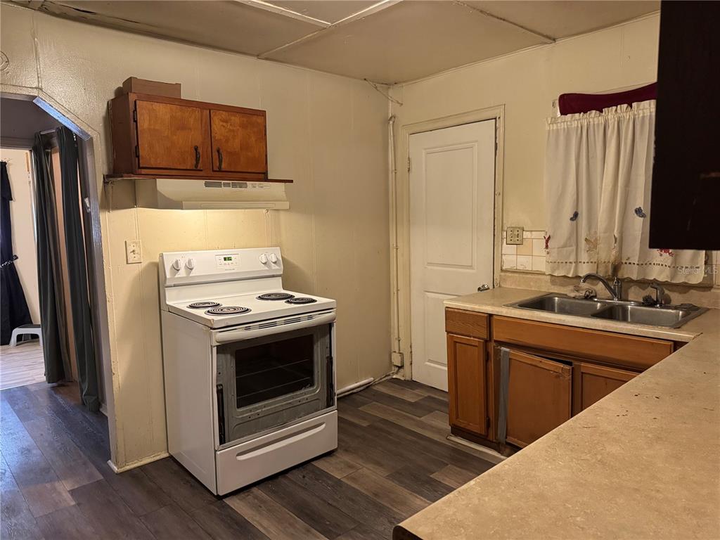 A kitchen features dark upper cabinets, wood lower cabinets, a microwave, and a double sink — 1049 PLATEAU AVENUE, LAKELAND, FL