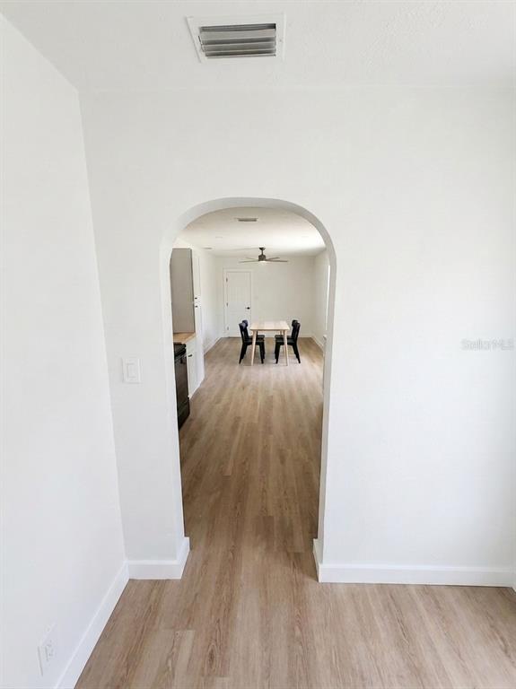 An arched doorway leads from a room with light wood flooring to a dining area — 1543 43RD STREET S UNIT B, ST PETERSBURG, FL