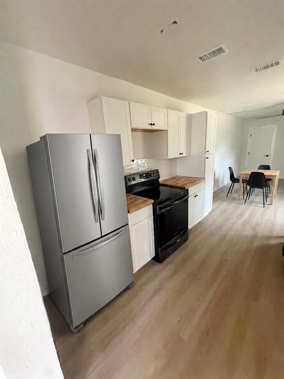 A kitchen features white cabinets, stainless steel appliances, and light wood-look flooring — 1543 43RD STREET S UNIT B, ST PETERSBURG, FL