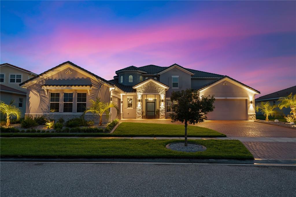 A two-story suburban house with a stone entryway, paved driveway, and a sunset sky — 840 SPINNAKER WAY, KISSIMMEE, FL