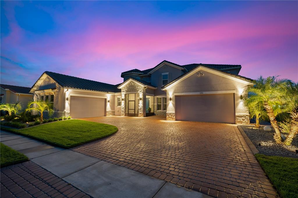 A two-story house with a paved driveway, two garages, and stone accents at dusk — 840 SPINNAKER WAY, KISSIMMEE, FL