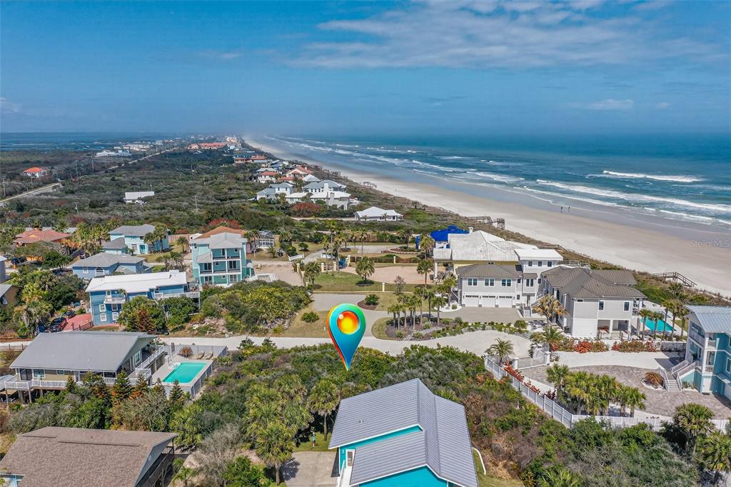 An aerial view shows a coastal neighborhood with houses, vegetation, and a sandy beach — 21 JESSICA LYNN PLACE, ST AUGUSTINE, FL