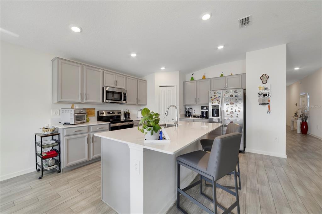 A kitchen with light gray cabinets, a central island, stainless steel appliances, and wood-look flooring — 5270 PRESERVE BOULEVARD, ST CLOUD, FL