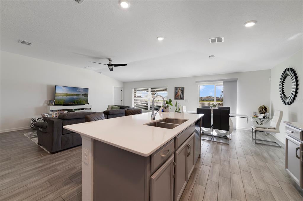 A kitchen island with a sink overlooks an open-concept living and dining area — 5270 PRESERVE BOULEVARD, ST CLOUD, FL