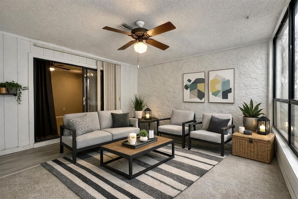 A sunroom features a gray sofa, two armchairs, a coffee table, and a striped area rug — 2834 SW 14TH DRIVE UNIT 305, GAINESVILLE, FL