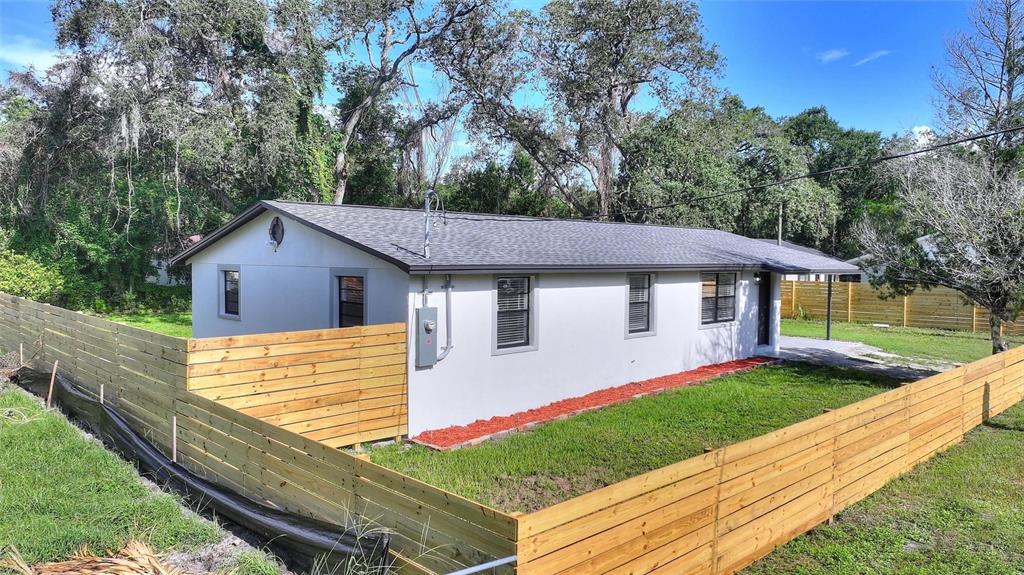 A single-story house with a light-colored exterior, a gray roof, and a new wooden fence — 10020 N 10TH STREET, TAMPA, FL