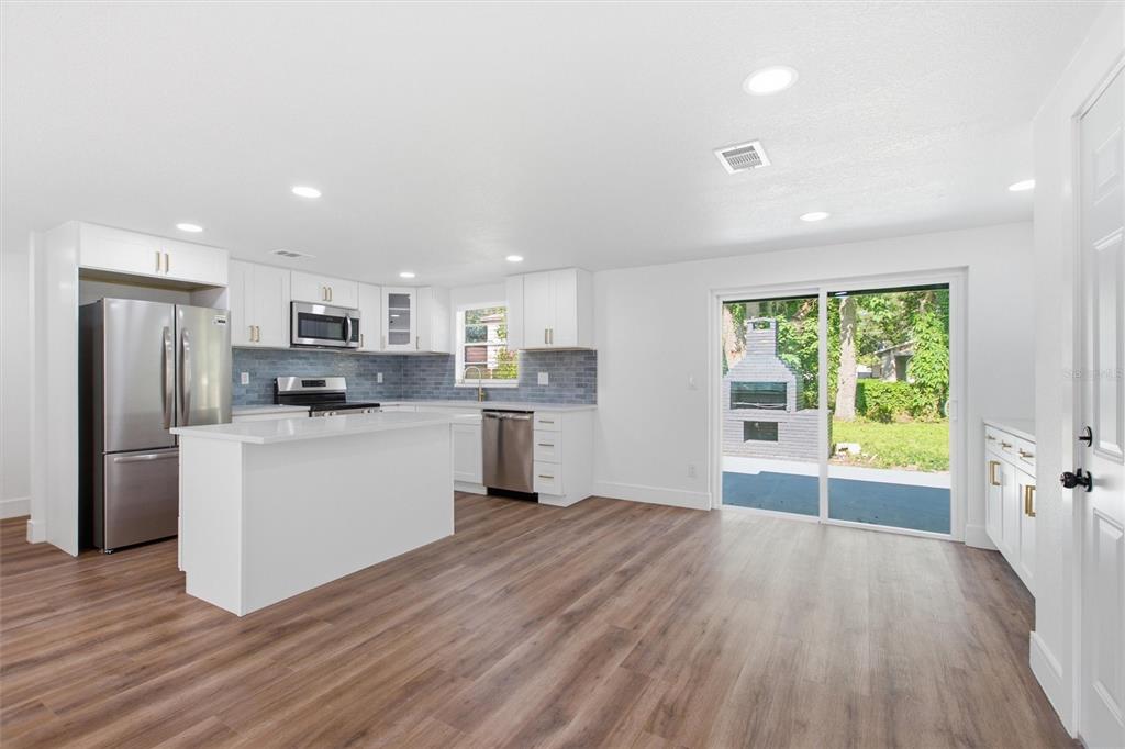 A bright kitchen with white cabinets, stainless steel appliances, and a sliding door to a patio — 10020 N 10TH STREET, TAMPA, FL