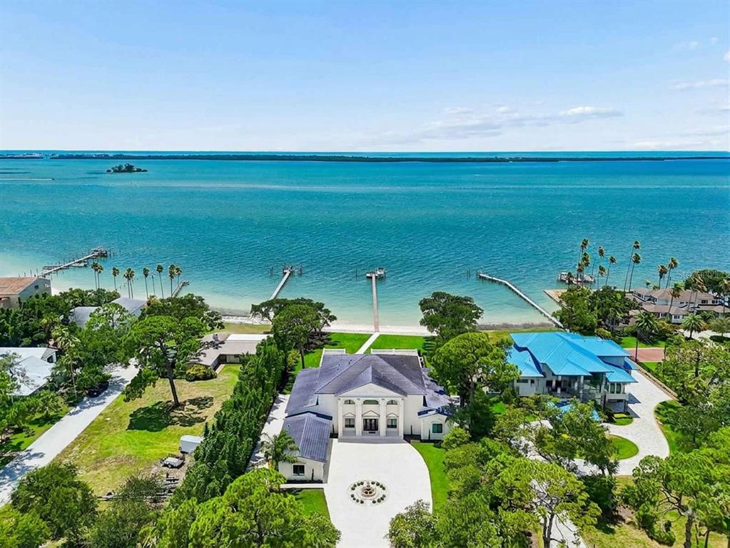 An aerial view of a large white house with a dark roof near the ocean — 1516 BAYSHORE BOULEVARD, DUNEDIN, FL