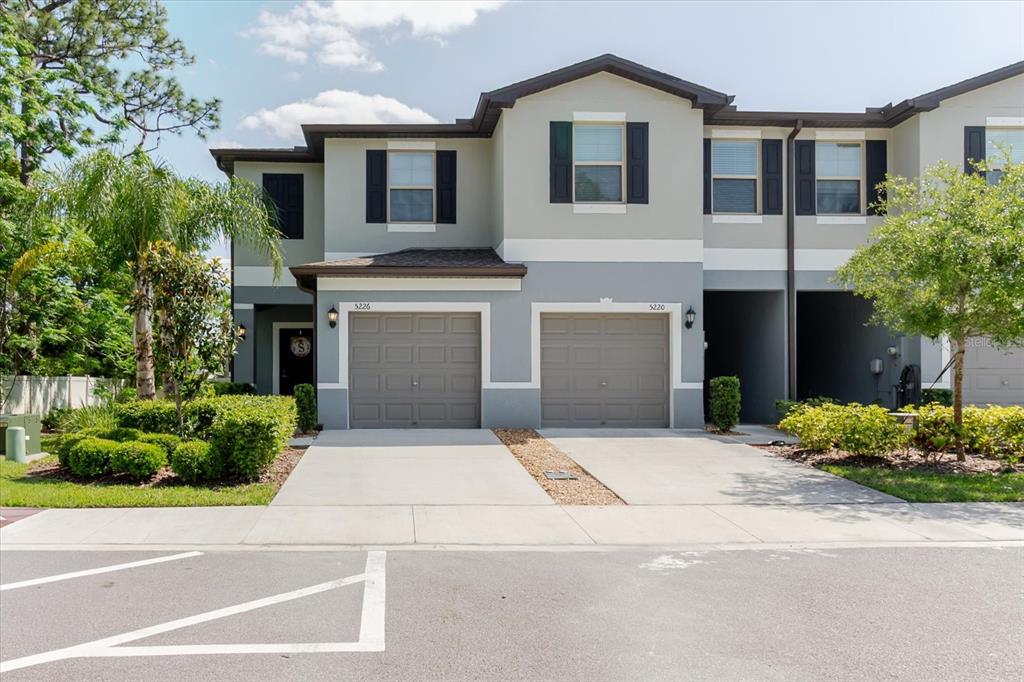 An aerial view shows two multi-story townhome buildings situated next to a wooded area — 5226 FORUM BOULEVARD, HOLIDAY, FL