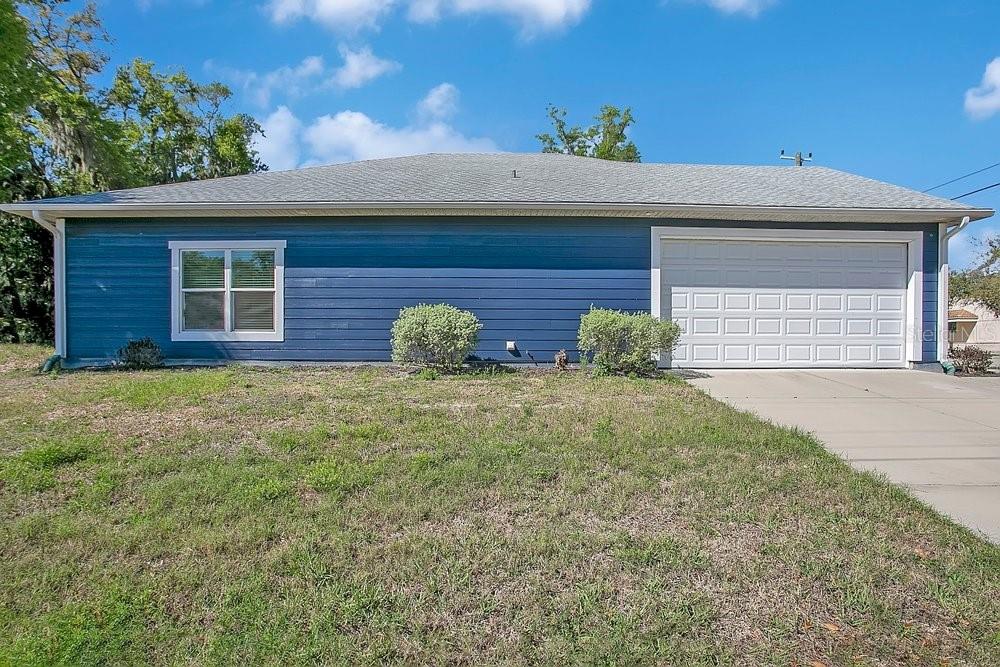 A blue, single-story house with a white garage door and a gray shingled roof — 2498 MITCHELL AVENUE, MIMS, FL