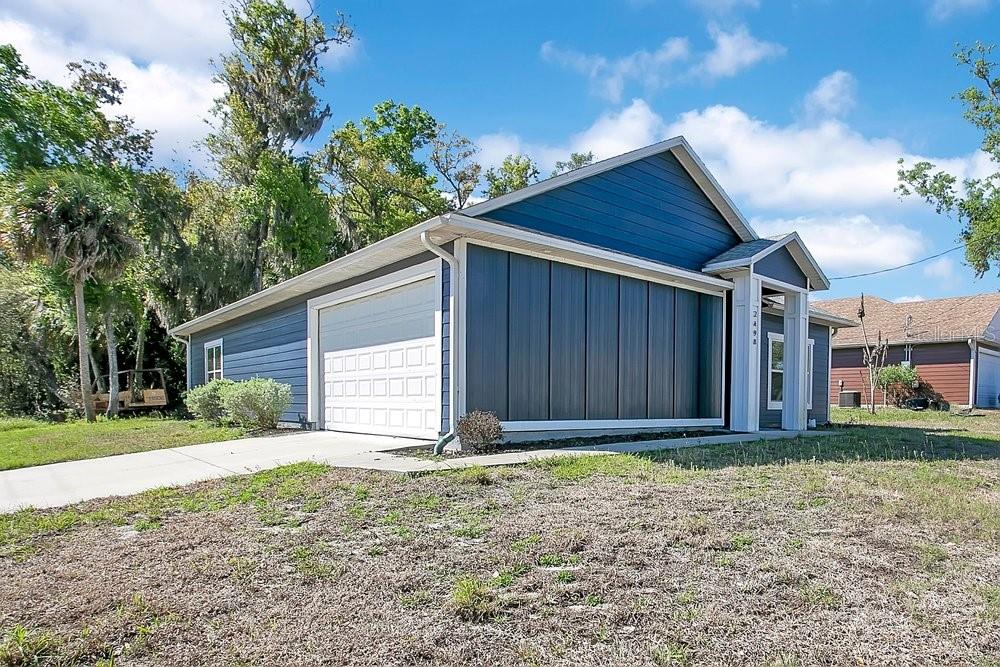 A blue house with a garage and a white front door under a small porch — 2498 MITCHELL AVENUE, MIMS, FL